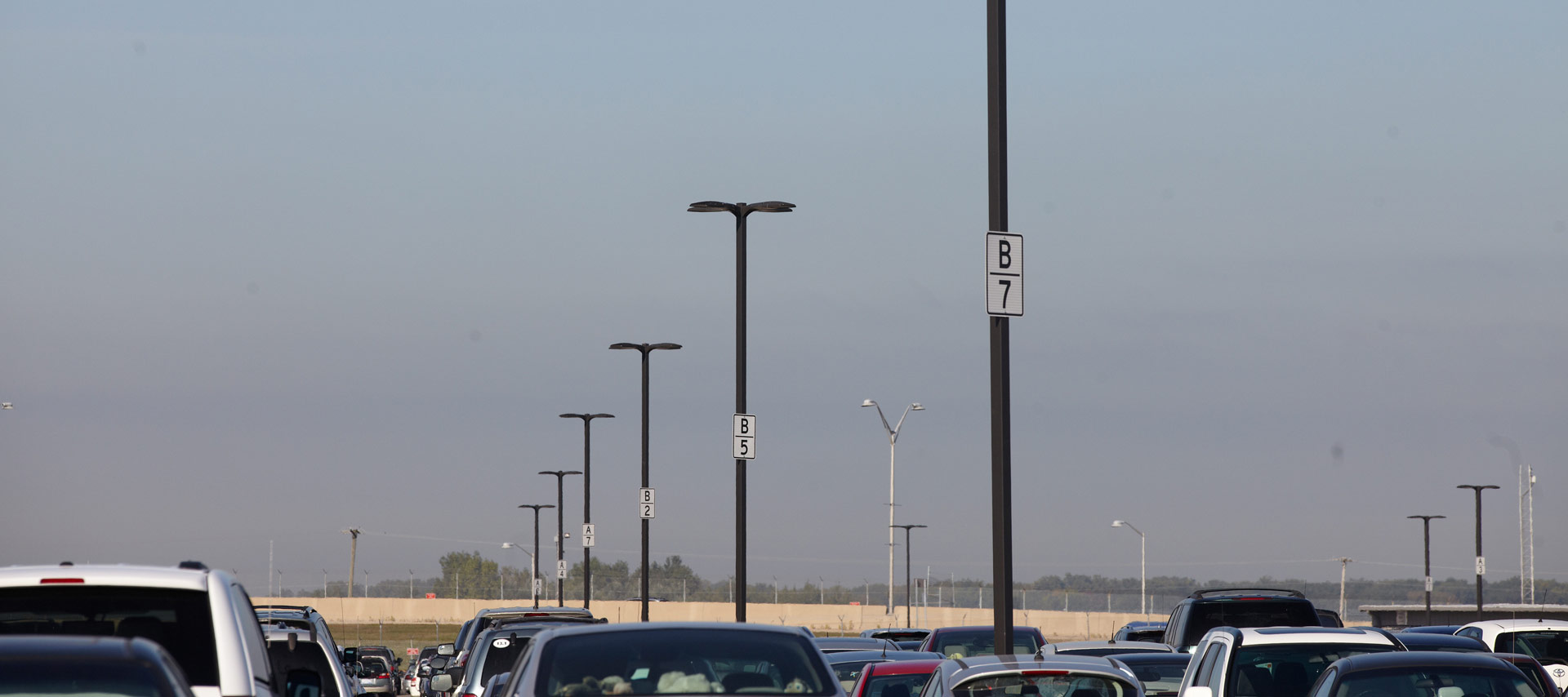 A variety of different types of light poles in a single parking lot.